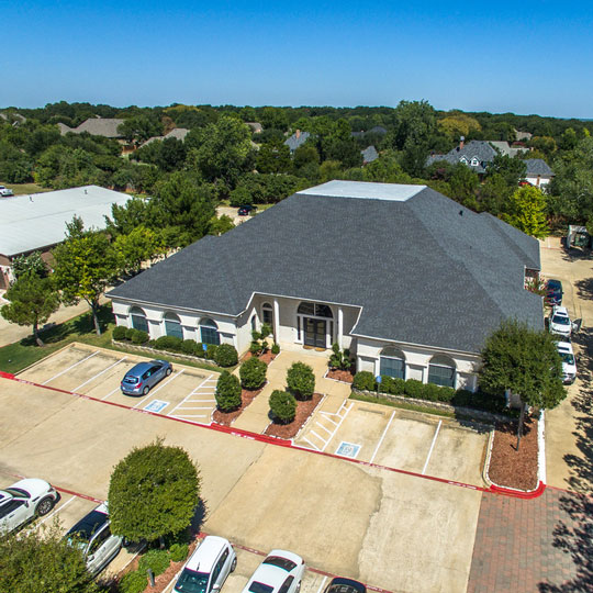 aerial photo of single story stucco commercial building with parking lot